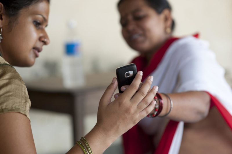 A community health worker shows a beneficiary a reminder SMS from her mobile data collection app