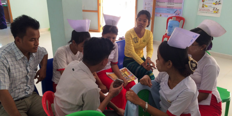 A supervisor reviews performance metrics with a group of community health workers